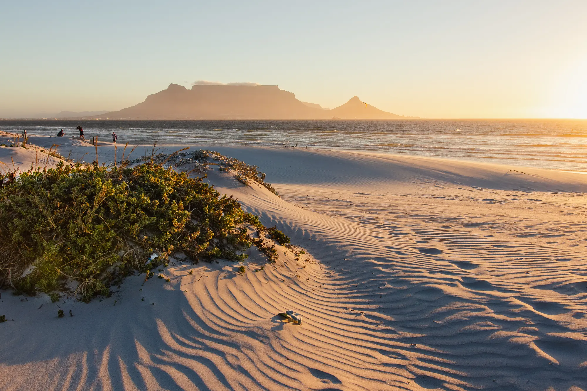 Wind-rippled sand dunes in warm evening light at Dolphin Beach, Table Mountain and Lion's Head silhouetted across the bay